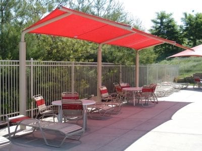 Outdoor seating with red sunshades and chairs.