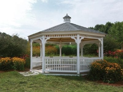 White gazebo surrounded by colorful garden flowers.